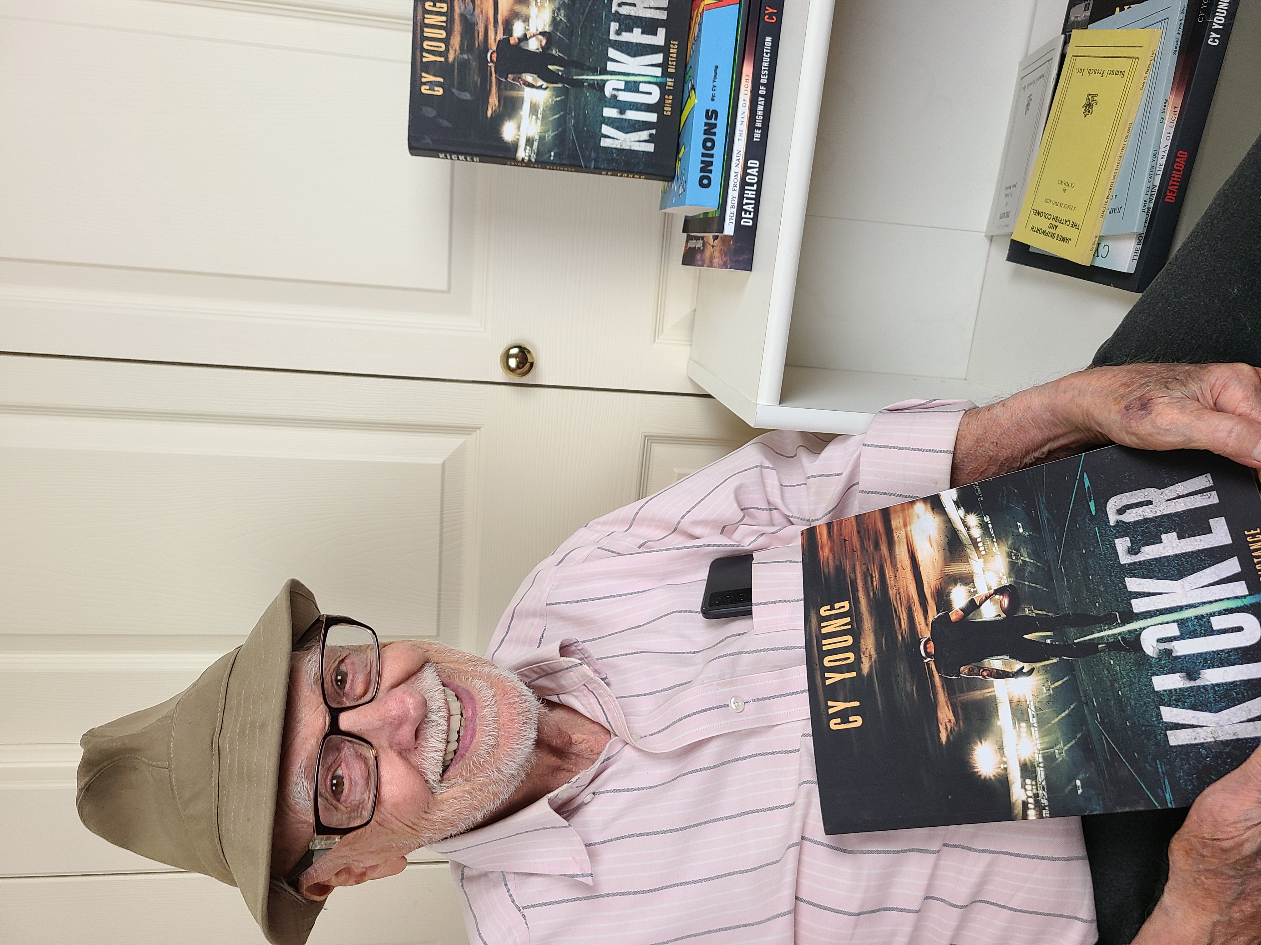 Photo of Cy Young wearing hat and holding the first book in the Kicker Series.